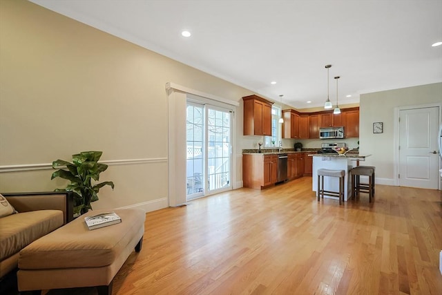 kitchen with light wood-type flooring, a breakfast bar, stainless steel appliances, pendant lighting, and a kitchen island