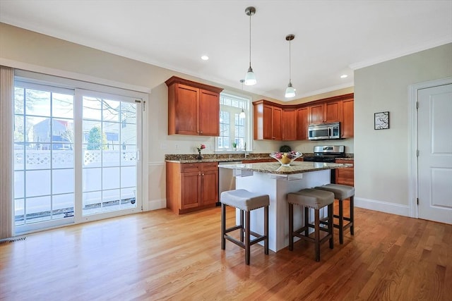 kitchen featuring light stone countertops, appliances with stainless steel finishes, light wood-type flooring, and a kitchen island