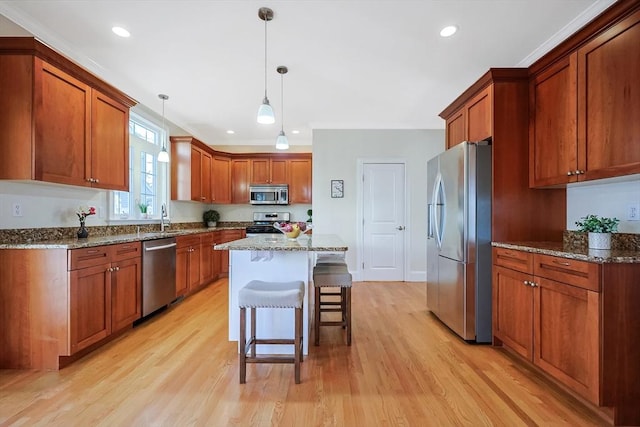 kitchen with hanging light fixtures, light hardwood / wood-style floors, a kitchen bar, a kitchen island, and appliances with stainless steel finishes