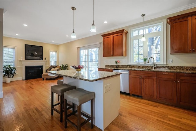 kitchen featuring dishwasher, a kitchen breakfast bar, sink, light hardwood / wood-style flooring, and decorative light fixtures