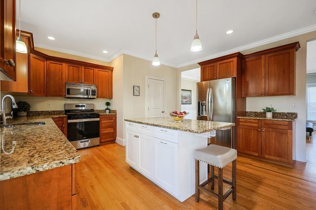 kitchen with sink, stainless steel appliances, decorative light fixtures, and light hardwood / wood-style flooring