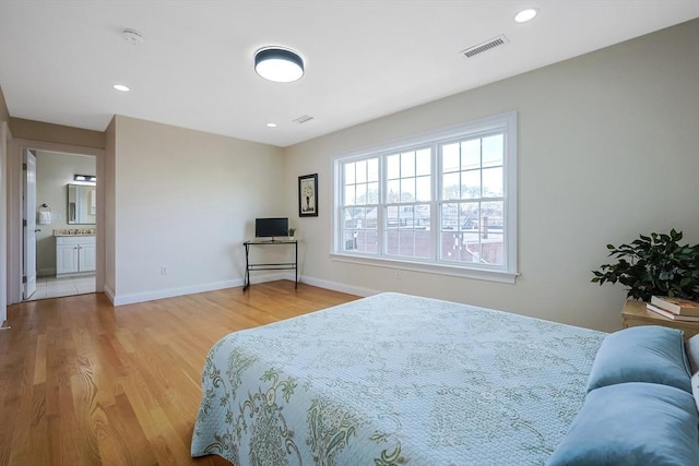 bedroom with ensuite bath and hardwood / wood-style floors