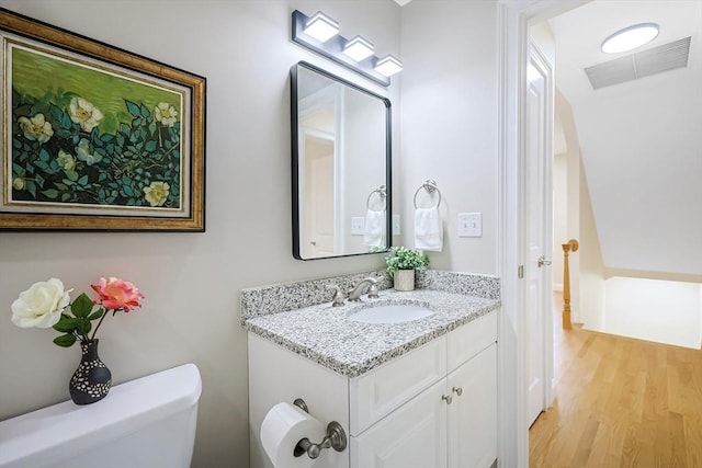 bathroom with hardwood / wood-style floors, vanity, and toilet