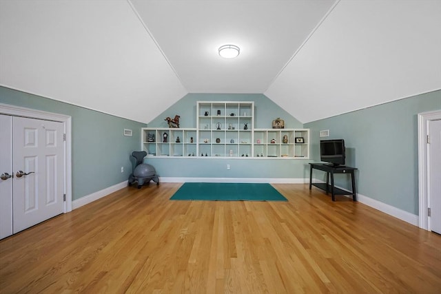 exercise area with wood-type flooring, built in features, and vaulted ceiling