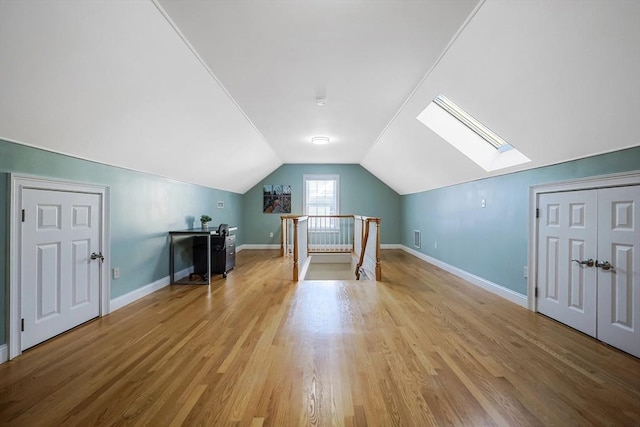 bonus room with light hardwood / wood-style floors and vaulted ceiling with skylight