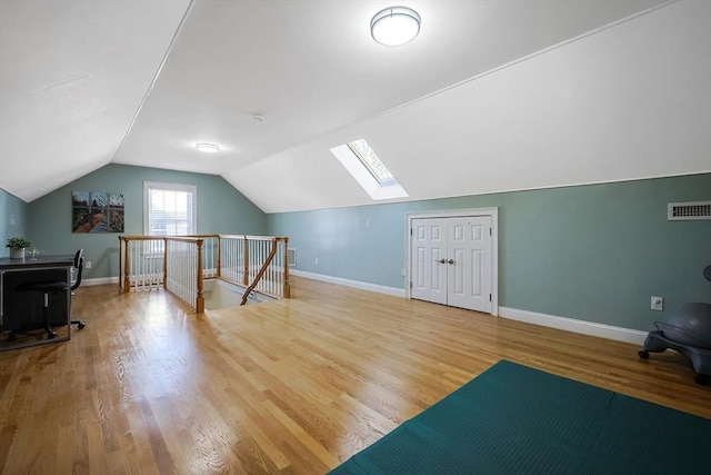 bonus room with light hardwood / wood-style flooring and vaulted ceiling with skylight