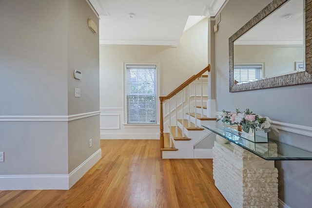 stairs with wood-type flooring, a wealth of natural light, and ornamental molding