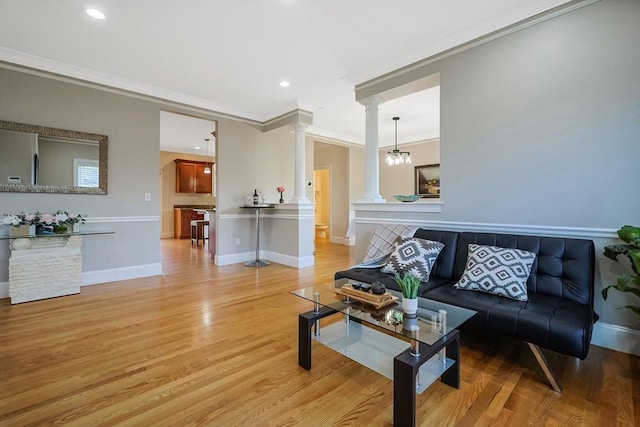 living room featuring an inviting chandelier, light hardwood / wood-style flooring, and crown molding