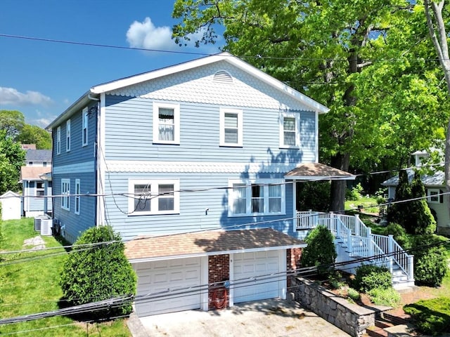 victorian house with concrete driveway, a garage, central AC unit, and stairs