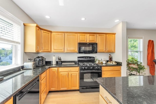 kitchen with black appliances, light wood-style floors, dark stone counters, and recessed lighting