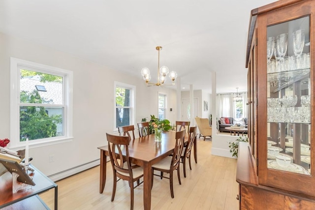 dining area featuring a chandelier, a baseboard heating unit, and light wood-style floors
