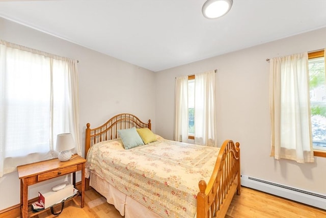 bedroom with baseboard heating and wood finished floors