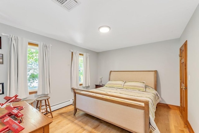 bedroom with light wood-style floors, a baseboard radiator, and baseboards