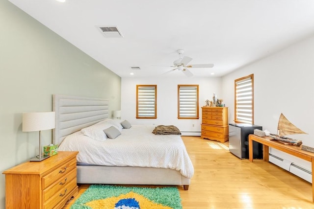 bedroom with multiple windows, a baseboard radiator, light wood finished floors, baseboard heating, and recessed lighting