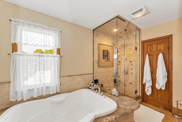 bathroom featuring a bath, a shower stall, and tile walls