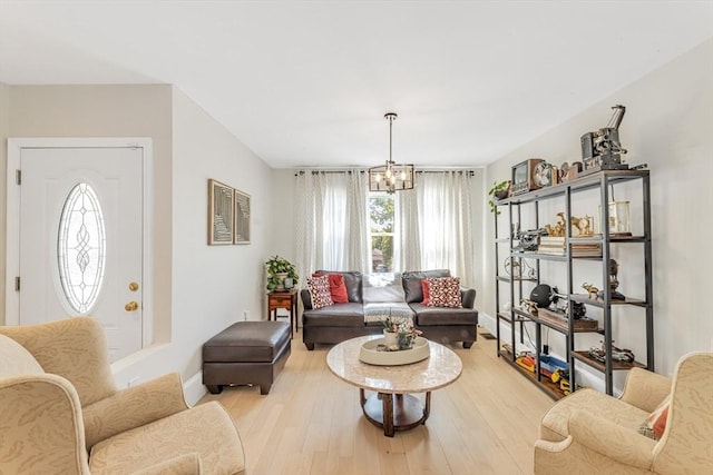 living room featuring a chandelier, light wood-style flooring, and baseboards
