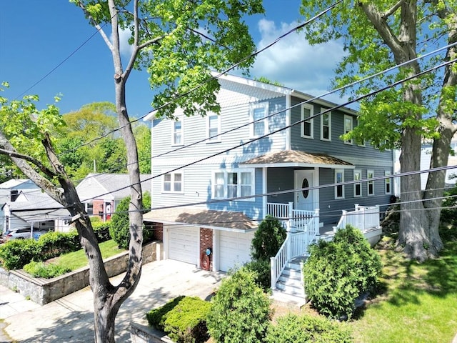 multi unit property featuring stairway, a garage, driveway, and brick siding