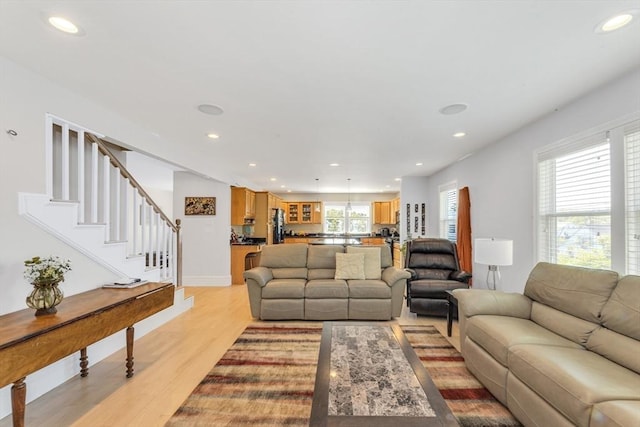 living room with light wood finished floors, recessed lighting, and stairs