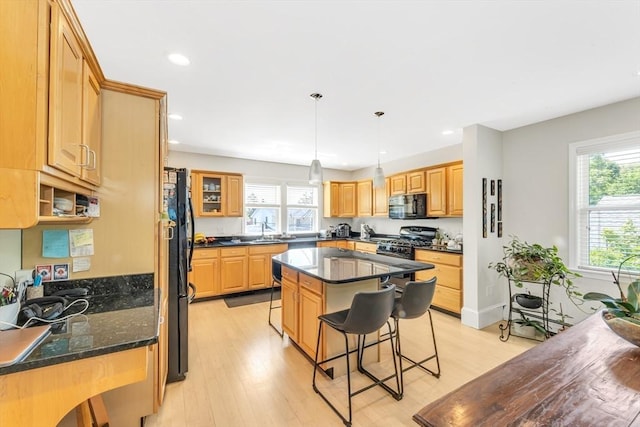 kitchen with black appliances, a kitchen breakfast bar, recessed lighting, light wood-style flooring, and a center island