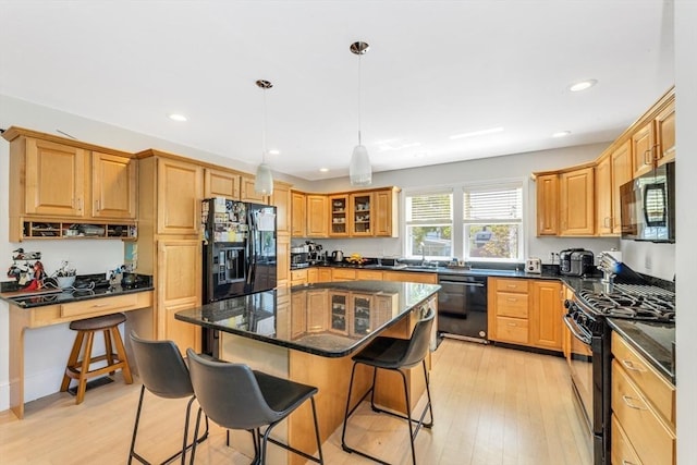 kitchen with black appliances, a breakfast bar area, light wood-style floors, a kitchen island, and recessed lighting