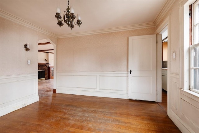 empty room featuring ornamental molding, wood-type flooring, and a chandelier