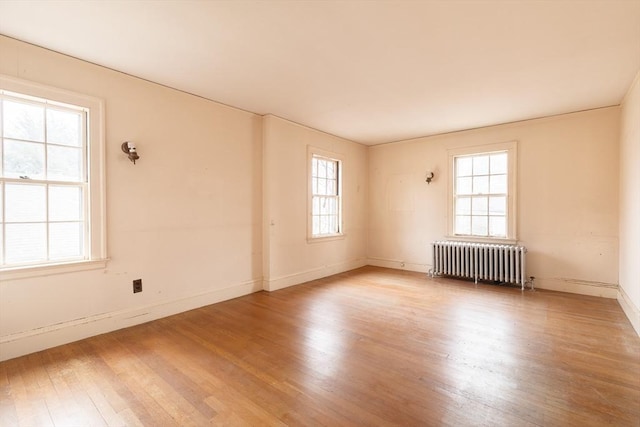 unfurnished room with hardwood / wood-style flooring, radiator, and a wealth of natural light