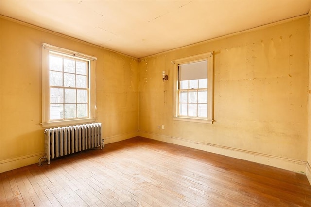 spare room featuring radiator and light hardwood / wood-style flooring