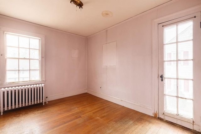 unfurnished room featuring ornamental molding, radiator, and light hardwood / wood-style flooring