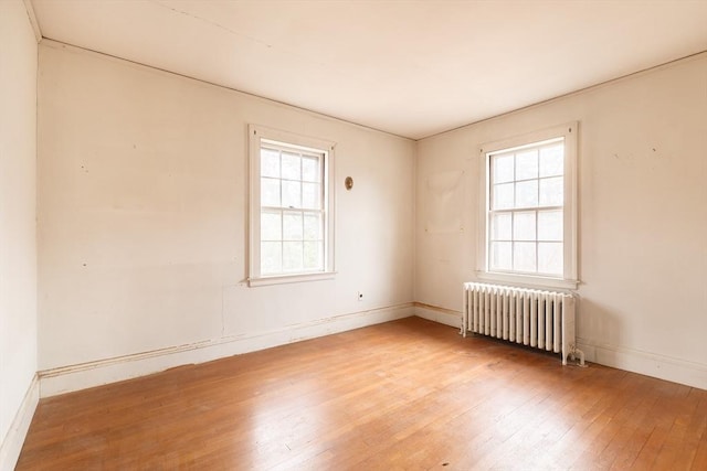 empty room featuring hardwood / wood-style floors and radiator heating unit