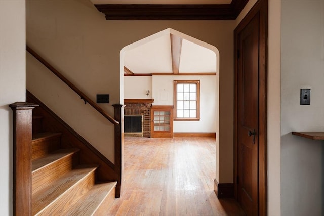 staircase with ornamental molding, a fireplace, and hardwood / wood-style floors