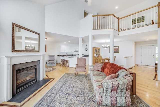 13 Laurel Hill Ct Unit 13, Bourne, MA 02532 - living area featuring a chandelier, light wood-style flooring, a towering ceiling, a fireplace, and recessed lighting