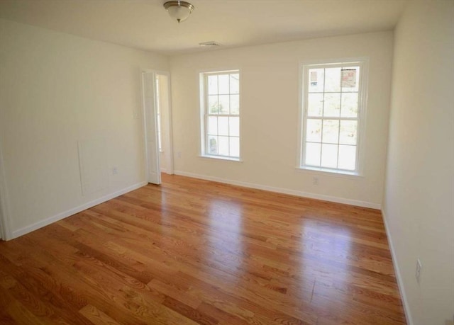 empty room with light hardwood / wood-style floors and a wealth of natural light