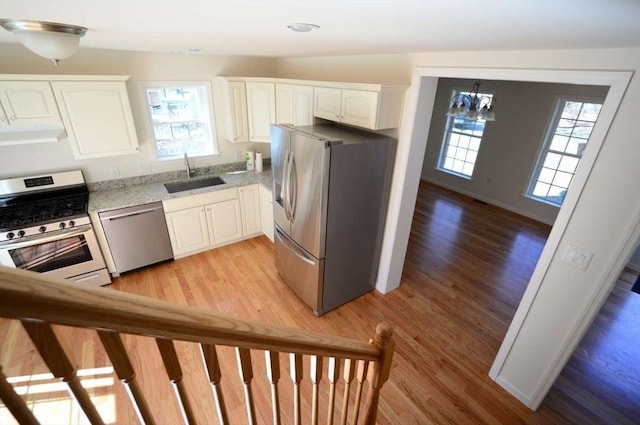 kitchen with sink, white cabinetry, hanging light fixtures, stainless steel appliances, and a wealth of natural light