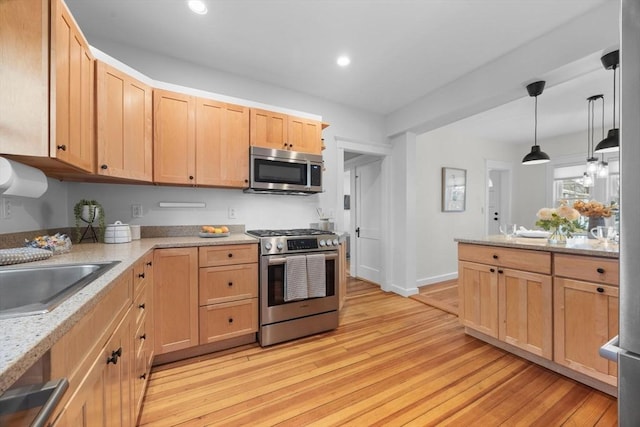 kitchen featuring hanging light fixtures, light brown cabinets, light hardwood / wood-style flooring, appliances with stainless steel finishes, and light stone countertops