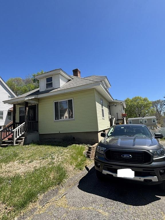 view of side of home with a chimney and a lawn