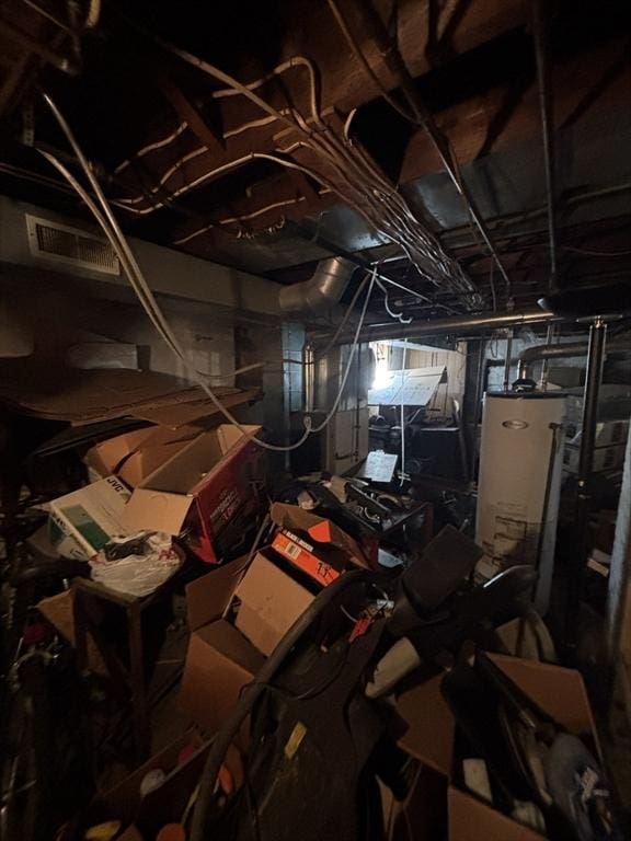 unfinished basement featuring water heater and visible vents