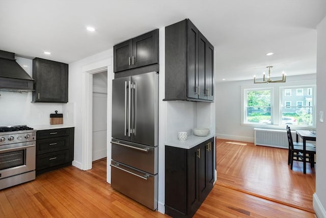 8 Carisbrooke St, Andover, MA 01810 - kitchen featuring stainless steel appliances, custom range hood, light wood-style flooring, radiator, and a chandelier