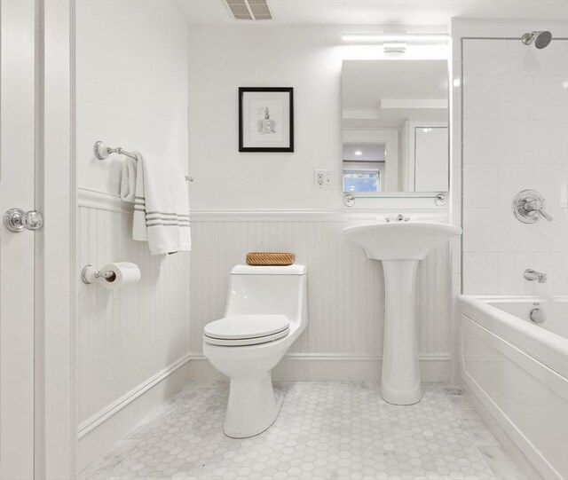 bathroom featuring visible vents, wainscoting, shower / tub combination, and toilet