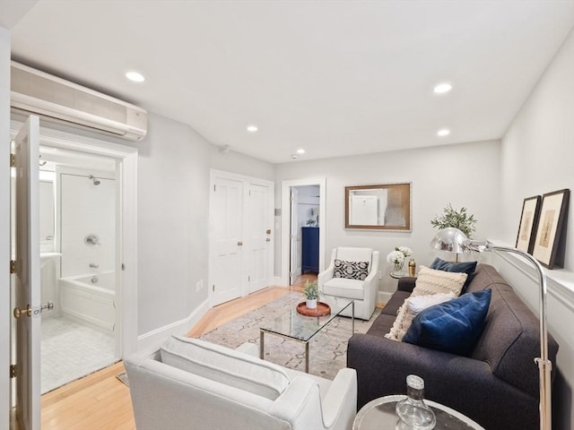 living area with an AC wall unit, recessed lighting, baseboards, and wood finished floors