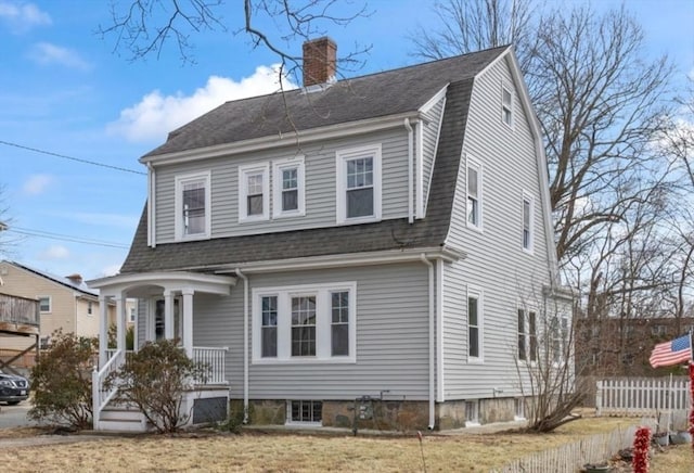 view of front facade featuring a gambrel roof, a porch, fence, roof with shingles, and a chimney