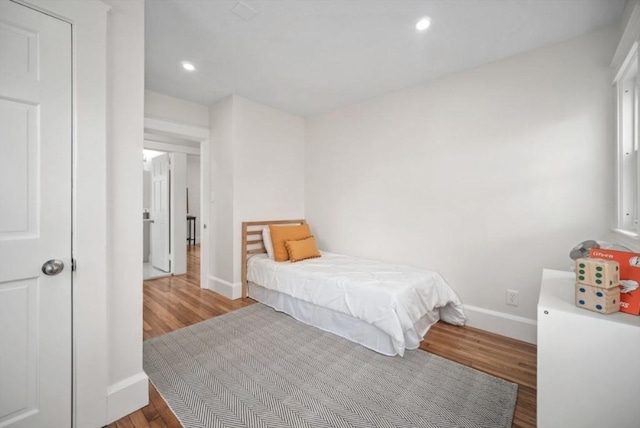 bedroom with recessed lighting, wood finished floors, and baseboards