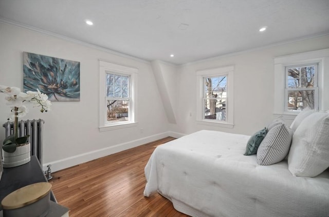 bedroom with wood finished floors, radiator heating unit, baseboards, and ornamental molding