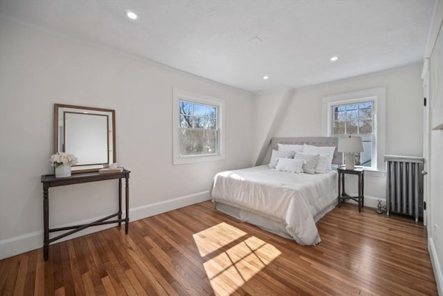 bedroom with multiple windows, radiator heating unit, baseboards, and wood-type flooring