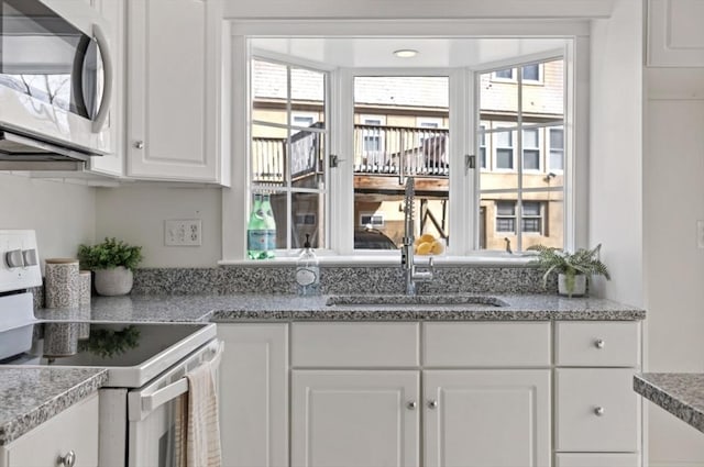 kitchen featuring white cabinetry, a sink, a wealth of natural light, and white range with electric stovetop