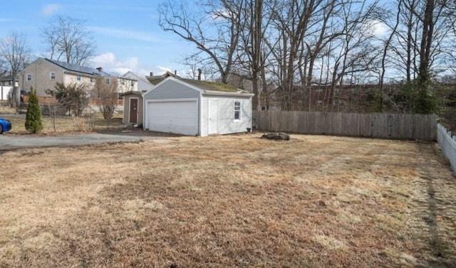 view of yard featuring a detached garage, an outdoor structure, and fence