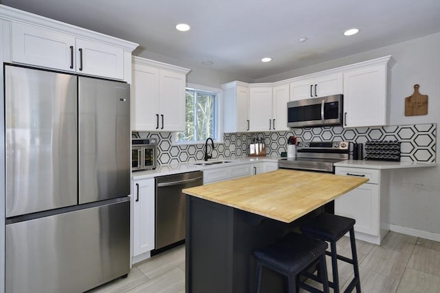 kitchen with sink, appliances with stainless steel finishes, white cabinets, and a center island