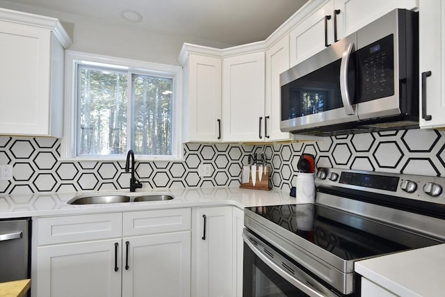 kitchen with white cabinets, stainless steel appliances, tasteful backsplash, and sink