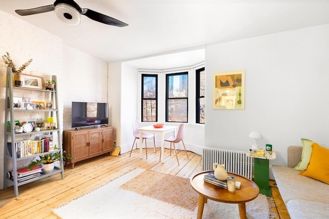 living room featuring radiator heating unit, light hardwood / wood-style floors, and ceiling fan