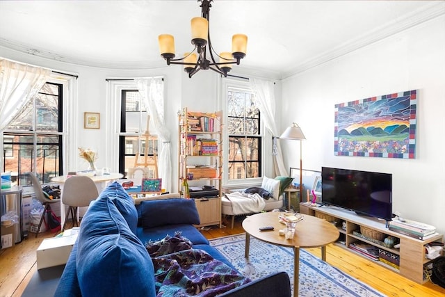 living room featuring wood-type flooring, ornamental molding, and an inviting chandelier