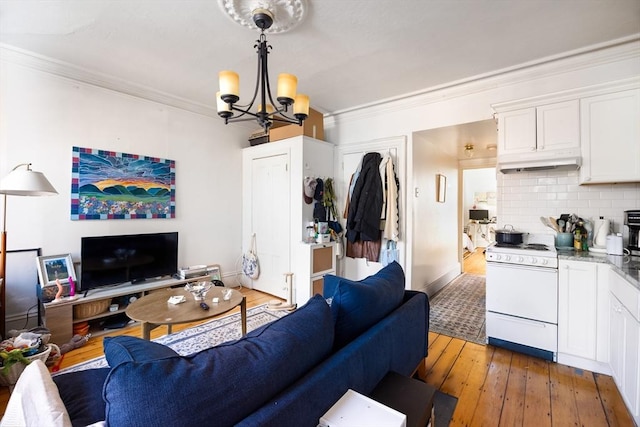 living room featuring dark wood-type flooring, ornamental molding, and a notable chandelier